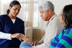 The caregiver gives medicine to the old man
